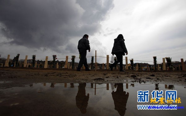 3月31日，在日本宫城县东松岛市，人们走过一处地震和海啸遇难者的临时集体墓地